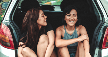 Two women laughing in back of car