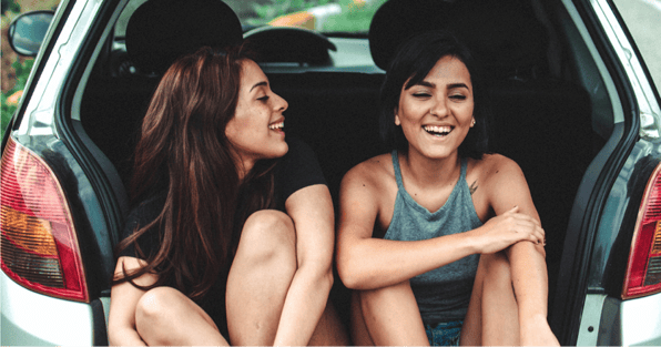 Two women laughing in back of car