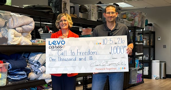Two people holding a check from Levo Cares Foundation for Call To Freedom