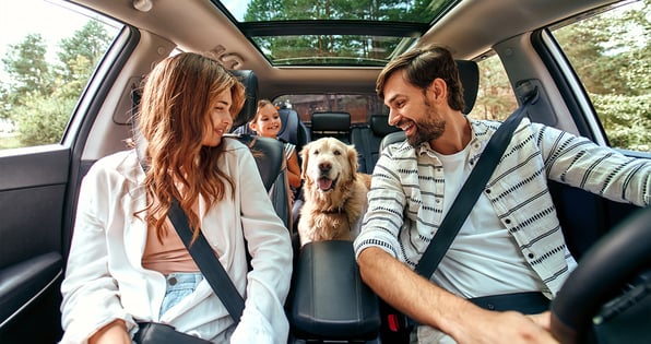 A happy family with a dog inside a car