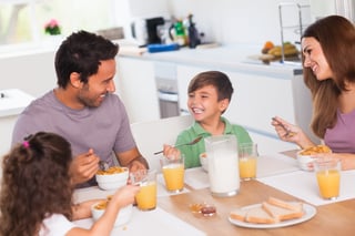 Family laughing around breakfast in kitchen