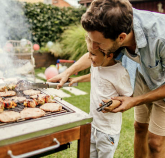 Father teaching young son how to bbq at a picnic