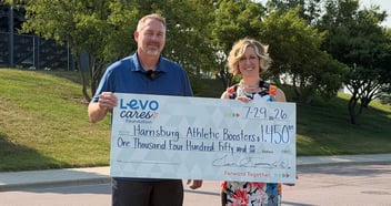 Two people hold a check from Levo Cares Foundation for the Harrisburg Athletic Boosters