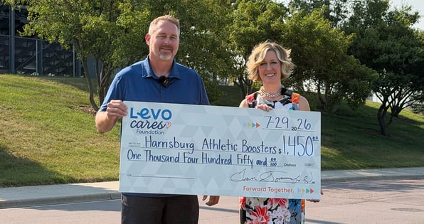 Two people hold a check from Levo Cares Foundation for the Harrisburg Athletic Boosters