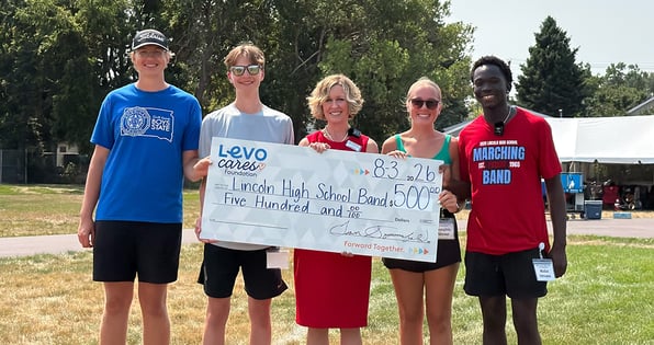 Five individuals hold a check from Levo Credit Union to the Lincoln High School Band