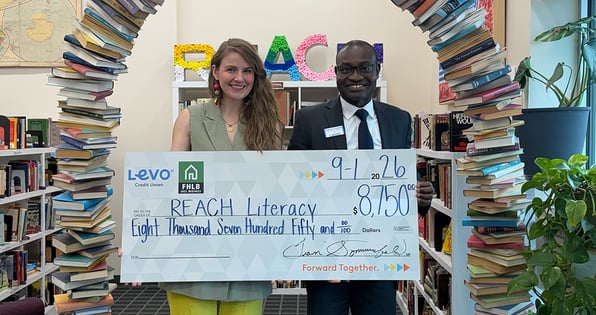 two people holding a check for Reach Literacy from Levo Credit Union